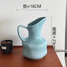 A light blue ceramic pitcher or vase with a handle, measuring about 16cm in diameter and 23cm in height.