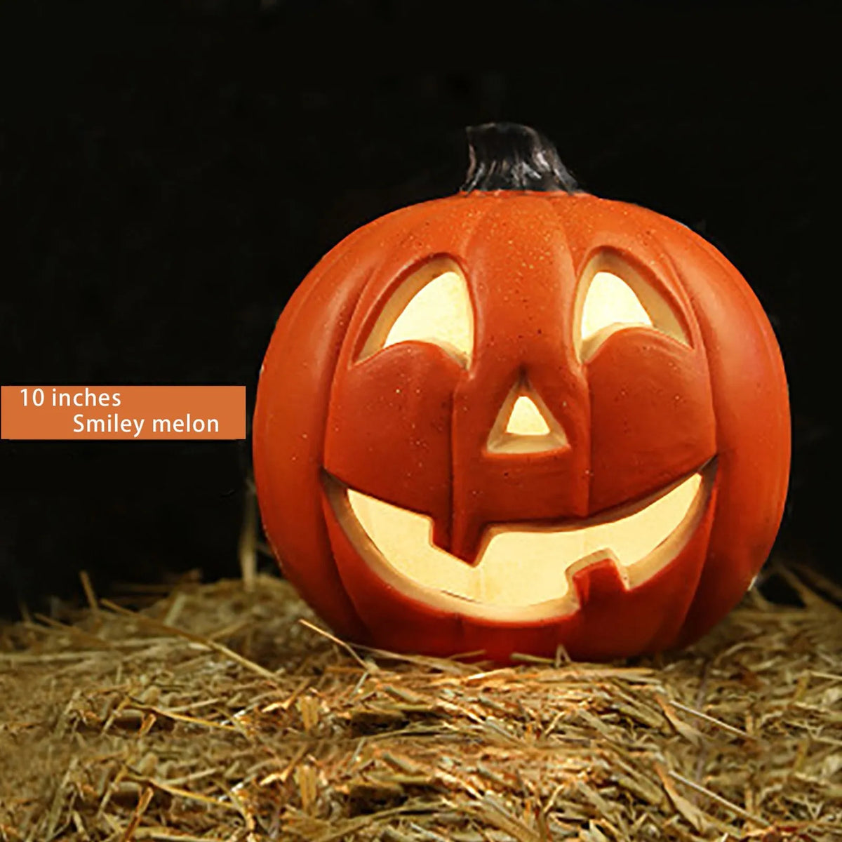 Linterna de calabaza de cerámica naranja tallada con cara sonriente sobre paja.