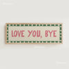 A framed canvas print with the text LOVE YOU BYE in pink lettering on a beige background with a green border.