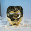 A highly reflective gold masquerade mask with an ancient style and hanfu-inspired design resting on white fabric.