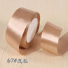 A roll of satin ribbon in a nude or champagne color is shown on a wooden surface.
