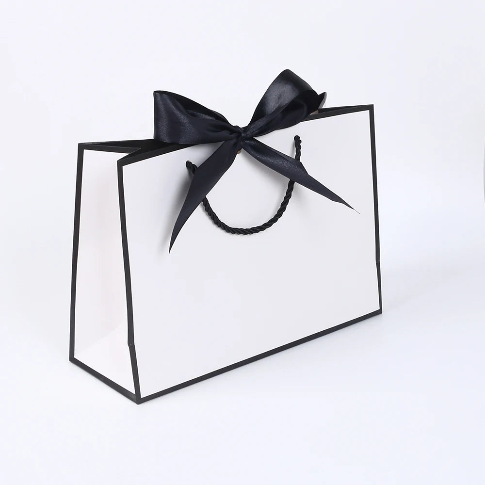 A set of five elegant black and white gift bags tied with black ribbon bows.