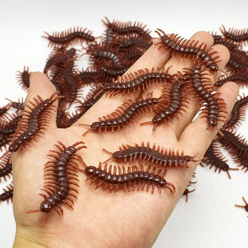 A hand holds a collection of realistic plastic insects including cockroaches, centipedes, and scorpions.