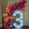 A large balloon garland in shades of pink and purple forms the number 3 for a celebration.