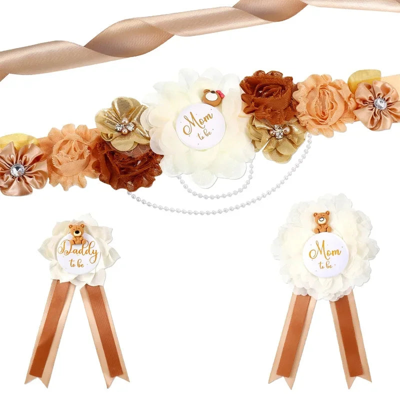A set of floral maternity sash and corsage pins featuring peach, brown, and cream flowers with gold accents.