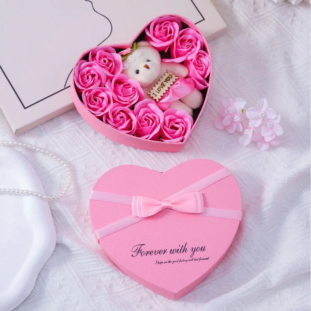 Pink heart-shaped gift box containing artificial roses and a white plush bear