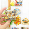 A hand holds a Scottish Highland Cow fridge magnet featuring a 3D shaggy cow with a calf, set against a white background.
