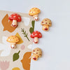 A set of nine cute decorative mushroom fridge magnets in various colors and styles against a light background.