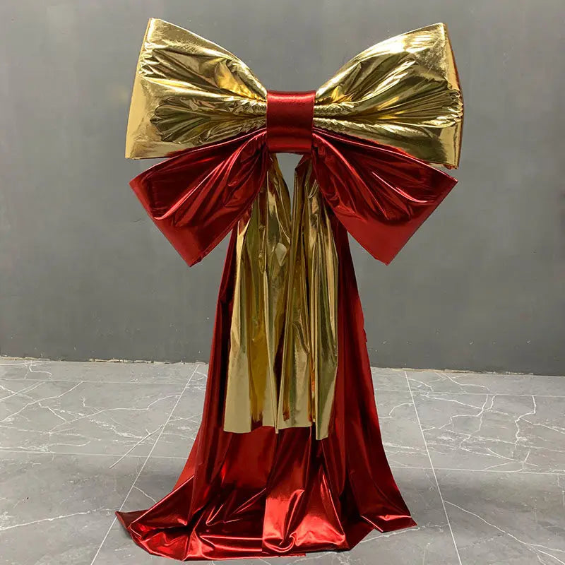 A giant satin bow in gold and red with a long tulle drape for event decor.