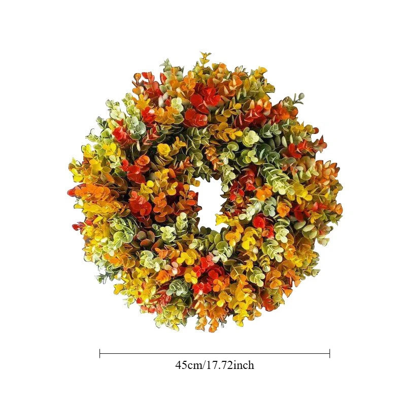 A circular wreath made of artificial flowers in shades of orange, yellow, and green for home decor