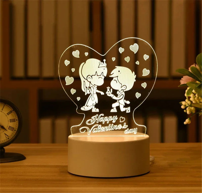 A heart-shaped acrylic night light featuring two cartoon figures and small hearts, resting on a wooden surface.
