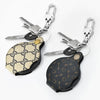 A pair of pocket magnifiers with leather cases and metal keychains, featuring a beige and black patterned design.