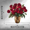 A bouquet of deep red roses in an amber glass pot with green leaves.