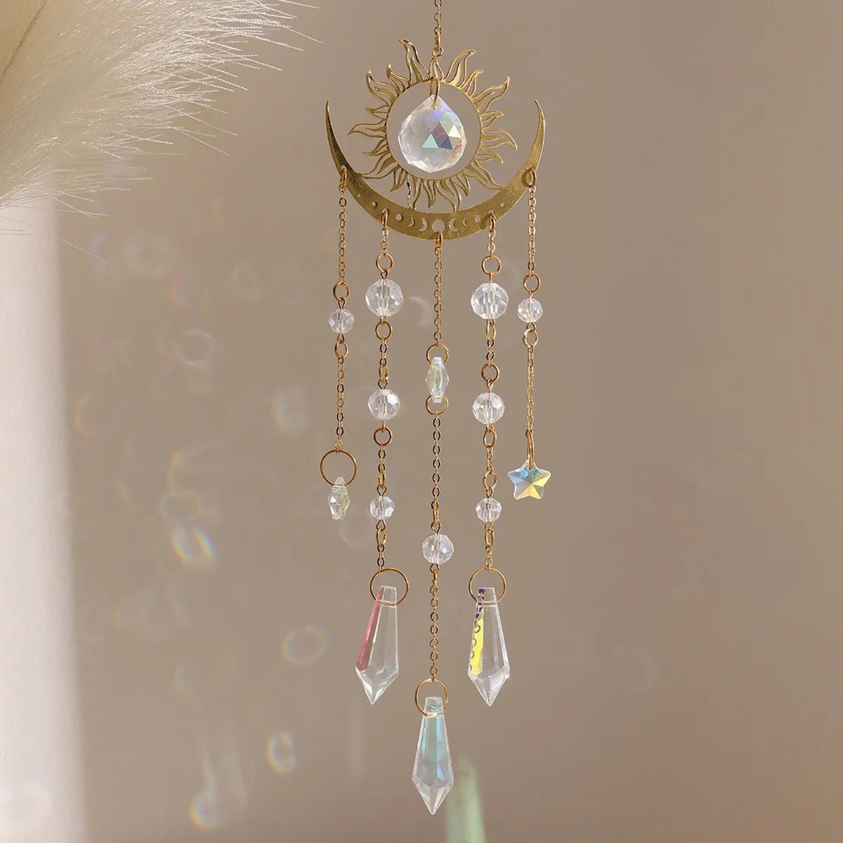 A gold flame moon crystal sun catcher featuring a crescent moon and hanging crystal beads and a star charm.