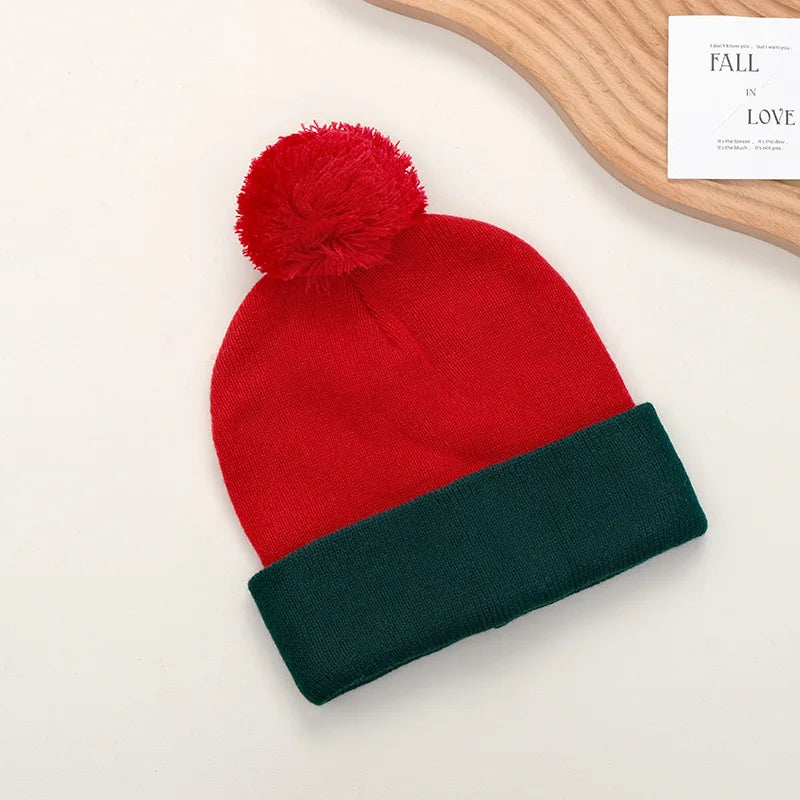 A bright red knitted beanie with a fluffy pom-pom and a dark green knitted glove is displayed on a light background.