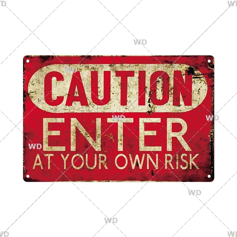 A vintage red metal warning sign with yellow text that reads CAUTION ENTER AT YOUR OWN RISK.