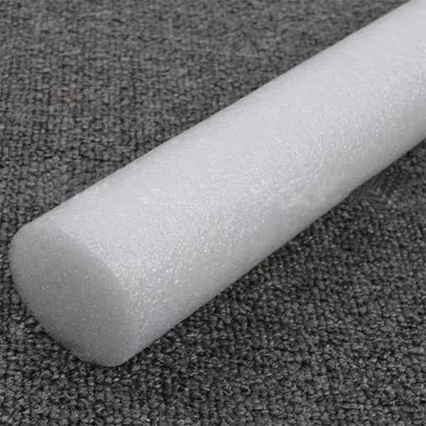 A white foam cylinder used for flower arrangements is shown lying on a dark gray textured surface.