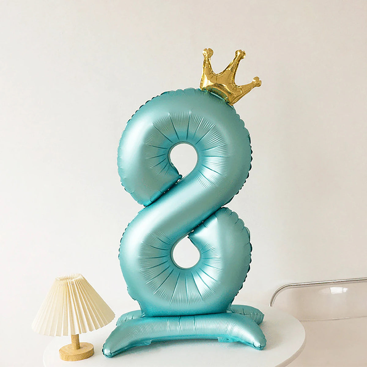 A light blue foil balloon shaped like the number eight with a gold crown on top.