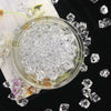 A clear glass jar filled with crystal ice cubes surrounded by loose acrylic stones and small clear crystals.