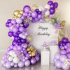A large balloon arch decoration featuring purple and gold latex balloons for a birthday celebration.