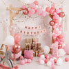 A large balloon arch decoration featuring pink and white balloons for a birthday party backdrop.