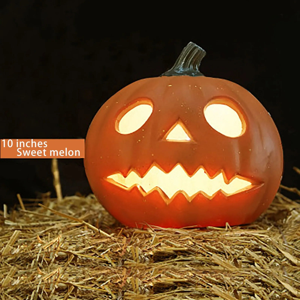 Calabaza de cerámica naranja tallada con ojos brillantes y una gran sonrisa, sobre paja.