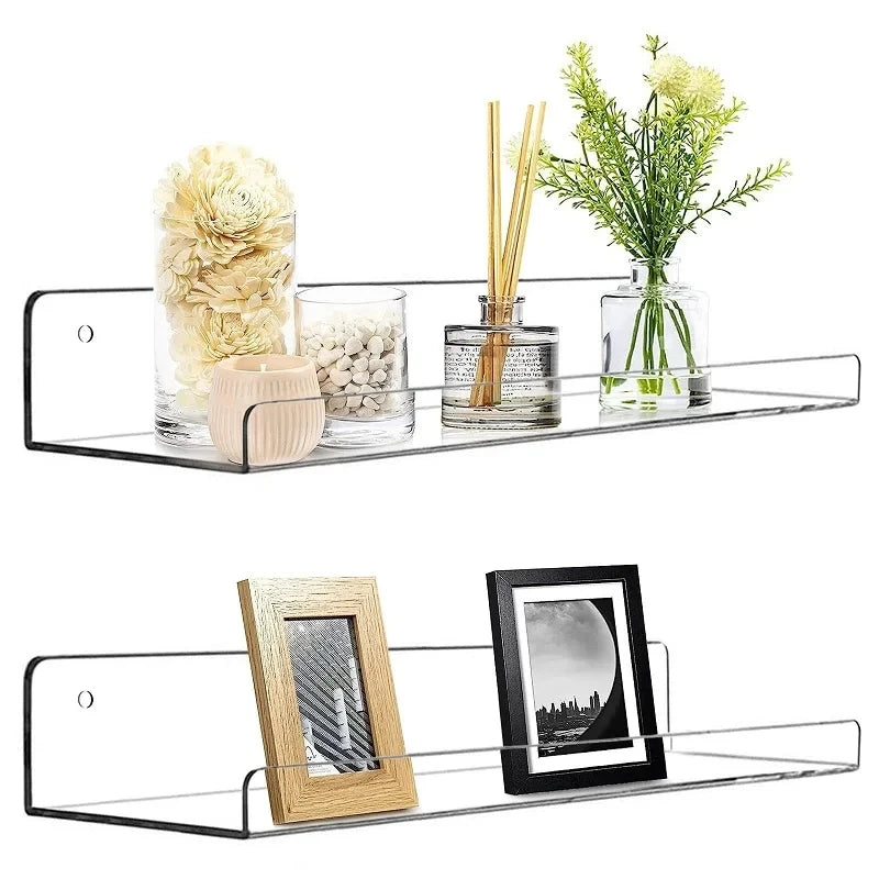 A clear acrylic floating shelf displaying dried flowers, glass jars, and a framed picture.