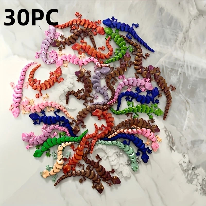 A collection of 30 individually colored, 3D printed articulated lizard figurines arranged in a scattered pattern on a white m