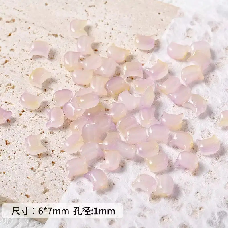 A pile of translucent pink cat head glass beads for jewelry making resting on white foam.