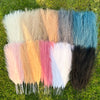 A collection of fifteen artificial reed bouquets in various shades of beige, pink, blue, and gray displayed on green grass.
