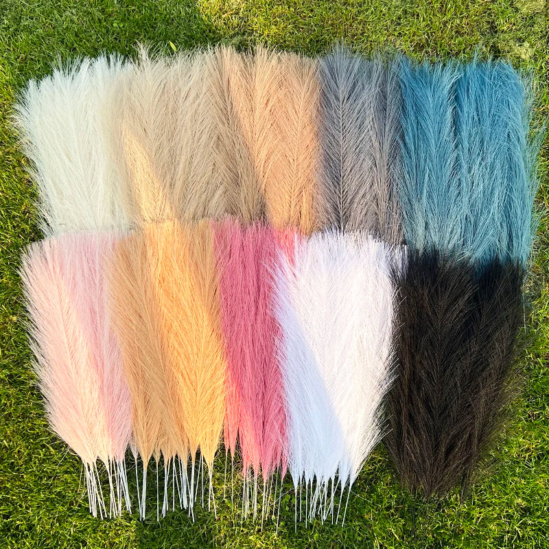 A collection of fifteen artificial reed bouquets in various shades of beige, pink, blue, and gray displayed on green grass.