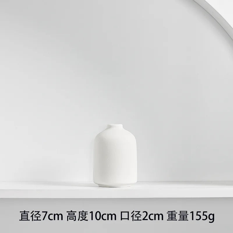 A white ceramic vase with a smooth, rounded shape is displayed on a white shelf.