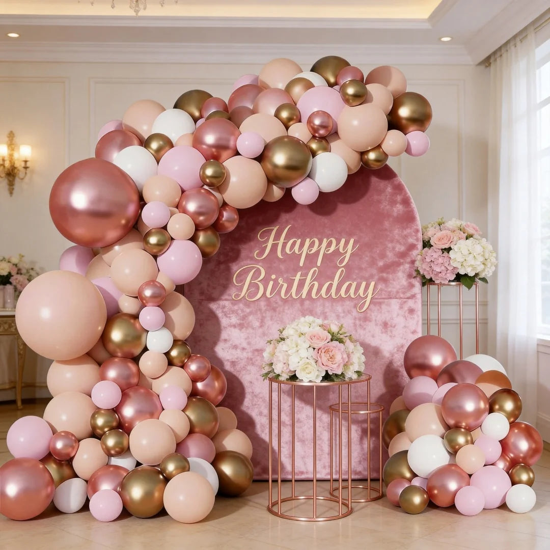 A large balloon garland featuring pink, rose gold, and cream balloons arranged in an arch against a pink backdrop.