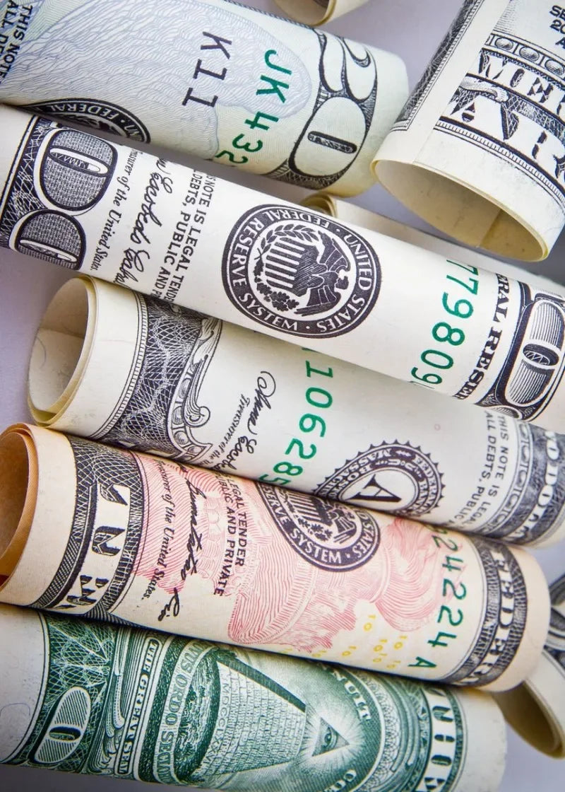 مجموعة من أوراق الدولار الأمريكي الملتفة والمطوية مكدسة معًا.