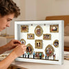 A white display case featuring gold-framed photos and figurines illuminated by LED lights.