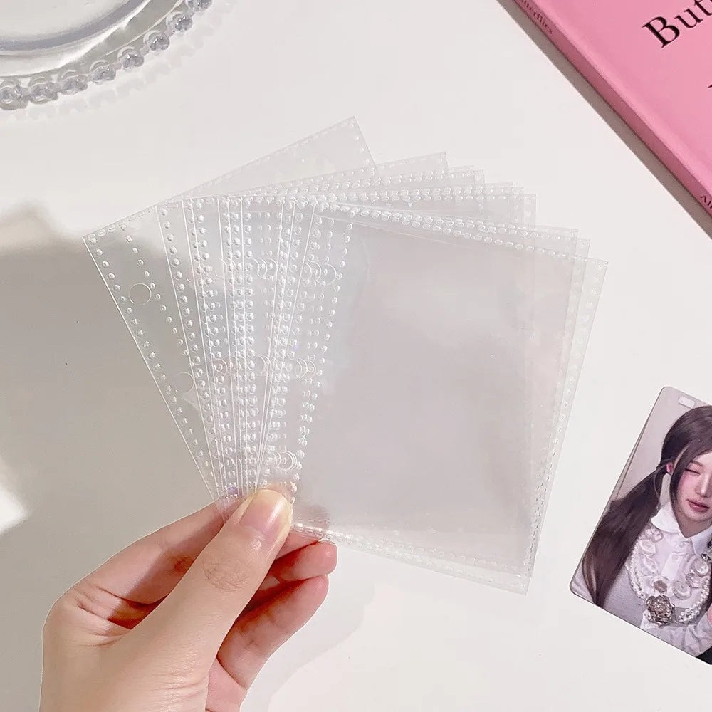 A hand holds a stack of clear glitter star card binders for collectibles on a white surface.