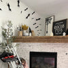 Black PVC bat wall decor hanging on a white wall above a rustic wooden mantelpiece.