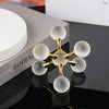 A minimalist molecular sculpture desk decor featuring gold and white spheres arranged in a branching structure.