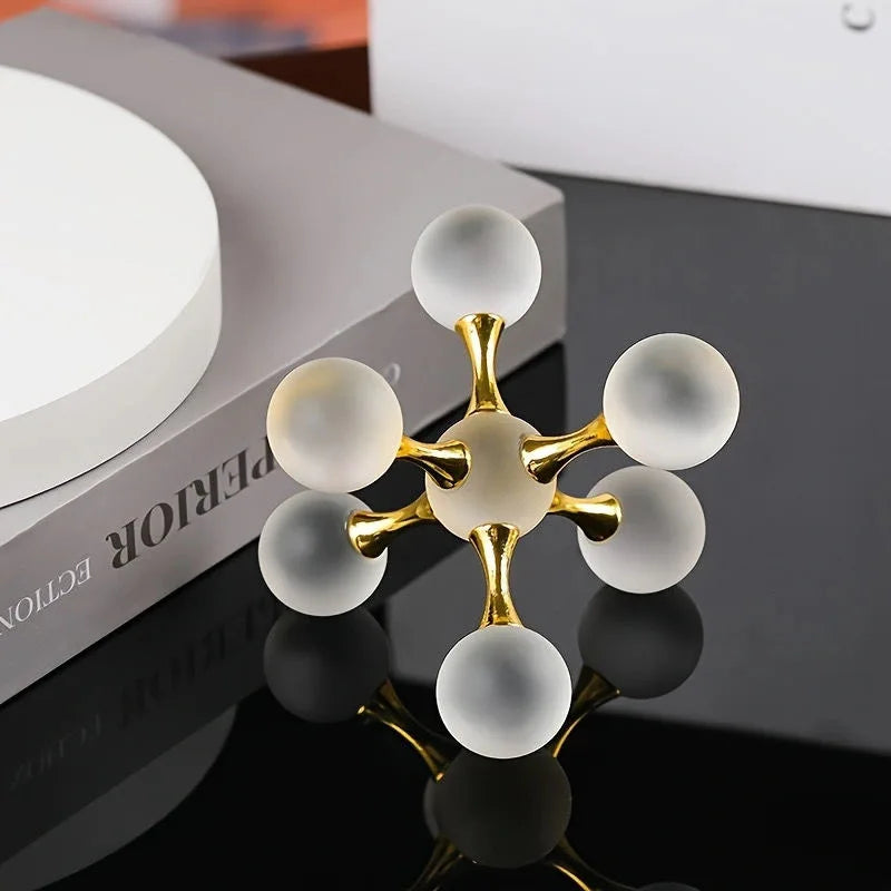 A minimalist molecular sculpture desk decor featuring gold and white spheres arranged in a branching structure.