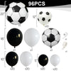 A collection of various sized black and white soccer balloons, including spheres and football shapes, for party decorations.