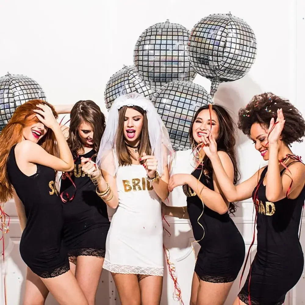 Six silver disco ball foil balloons are held by women in black dresses for party decorations.