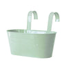 A light green modern boho metal hanging planter with curved metal arms.