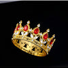 A gold crown featuring red gemstones and clear crystals, used as a cake topper.