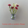 A small glass vase holding a sprig of red and white flowers, used for fridge decor.