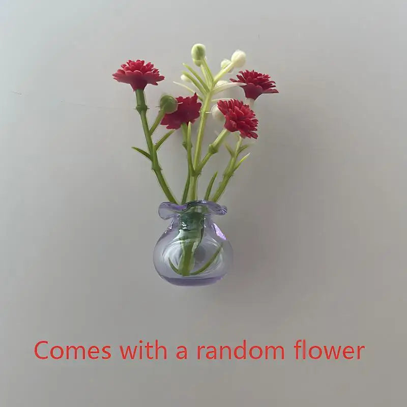 A small glass vase holding a sprig of red and white flowers, used for fridge decor.