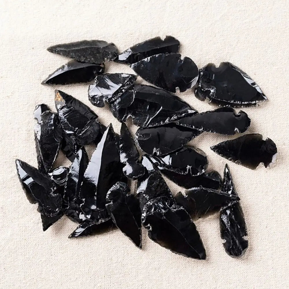 A pile of sharp, black obsidian arrow-shaped crystals used as a Reiki healing charm.