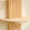 A vertical wooden wall shelf with a ribbed design and a horizontal shelf mounted on a white wall.