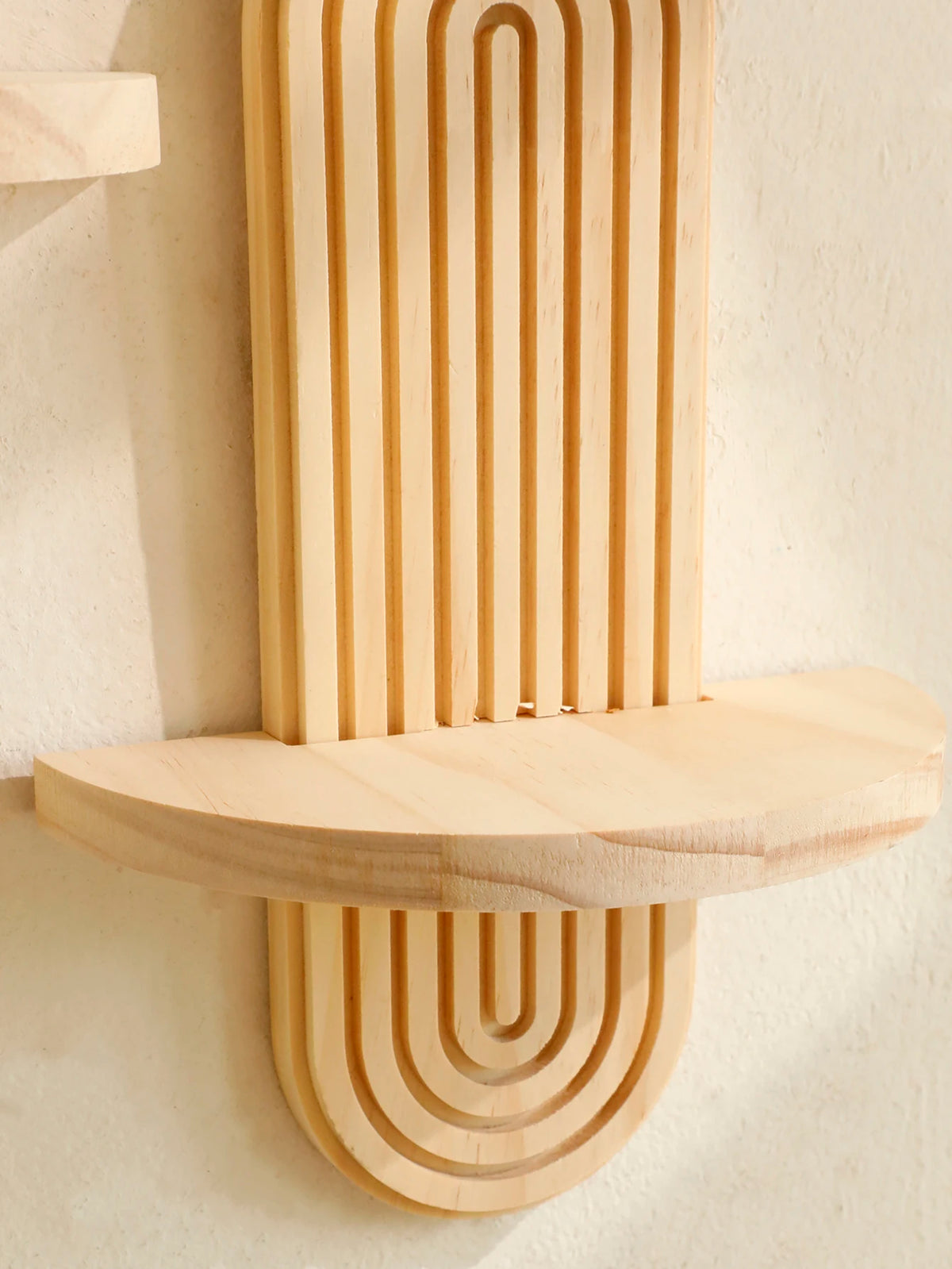 A vertical wooden wall shelf with a ribbed design and a horizontal shelf mounted on a white wall.