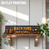 A rustic metal sign with the text Backyard Bar & Grill Welcome and Good Time mounted on a wooden plank.