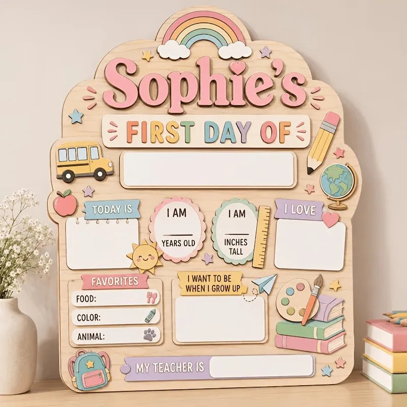 A wooden sign for a child's first day of school featuring illustrations like a school bus, rainbow, and various labels.